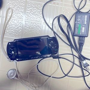 PSP with wrist strap, audio jack plug-in, and charger